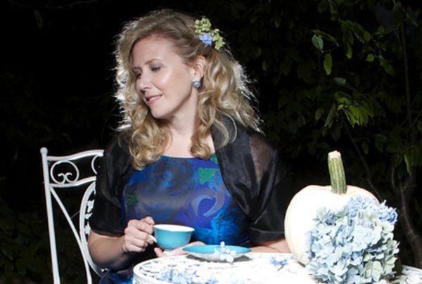 Lifestyle portrait Author Linda Brooks seated at white table during tea time