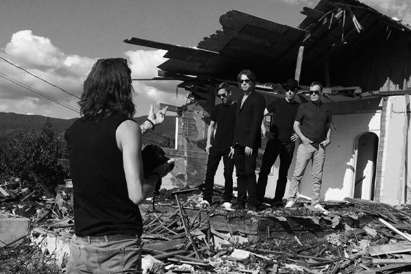 BTS photo black and white photographer Mark Maryanovich directing four members of 5440 standing in front of dilapidated building