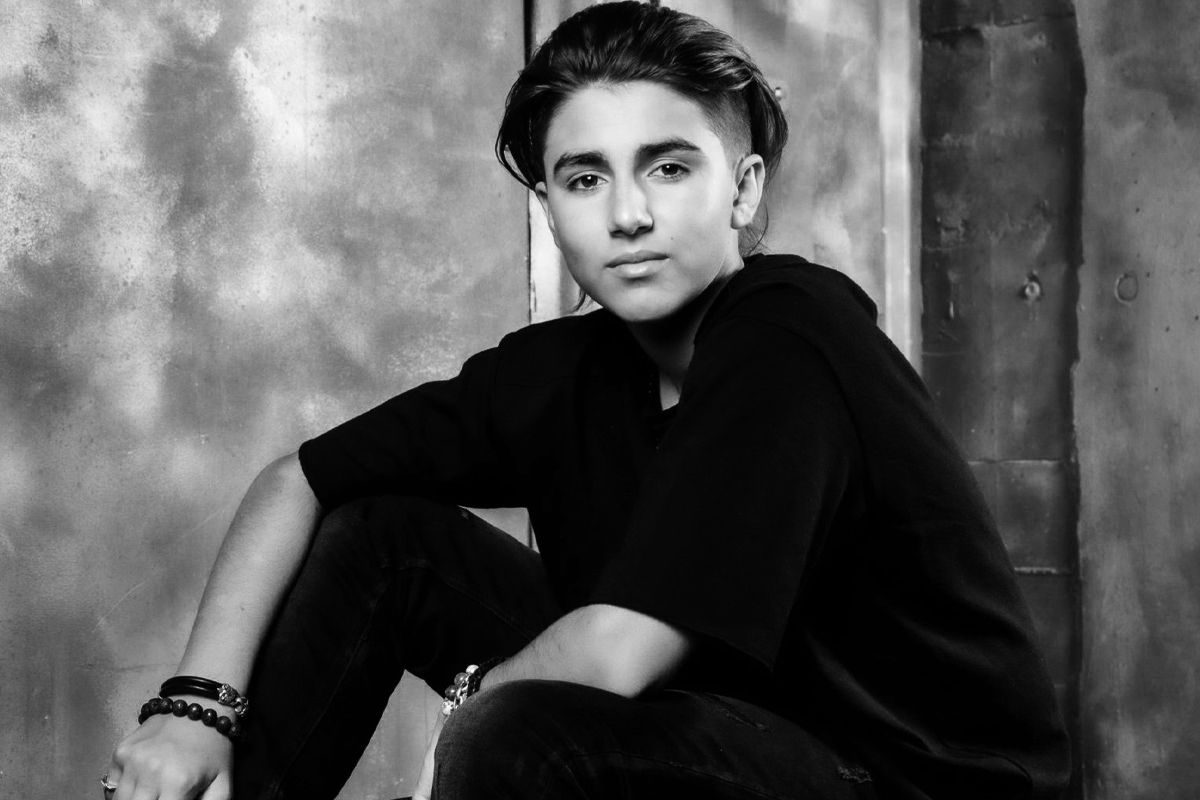 Tween personal branding photo black and white Dominique Ilie sitting against cement wall elbows resting on knees