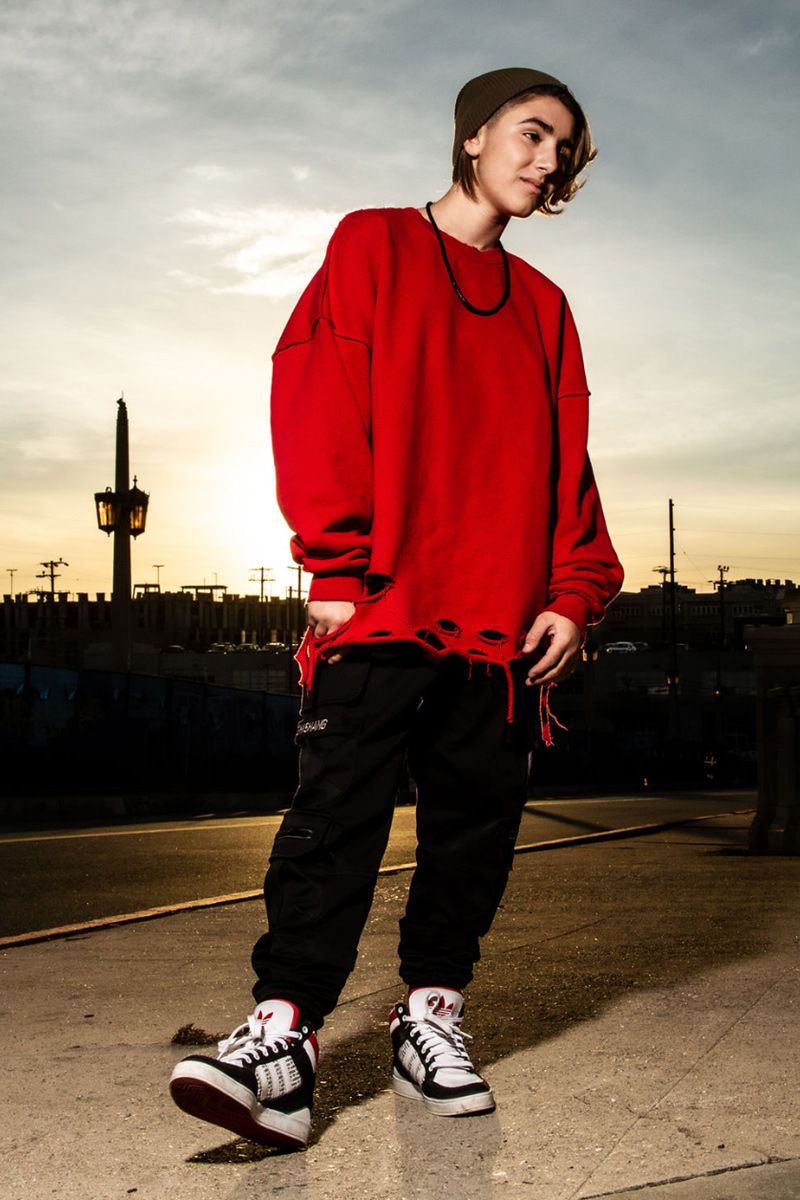 Dominique Ilie pre teen personal branding portrait full length shot wearing red sweatshirt black pants runners standing on street at sunset