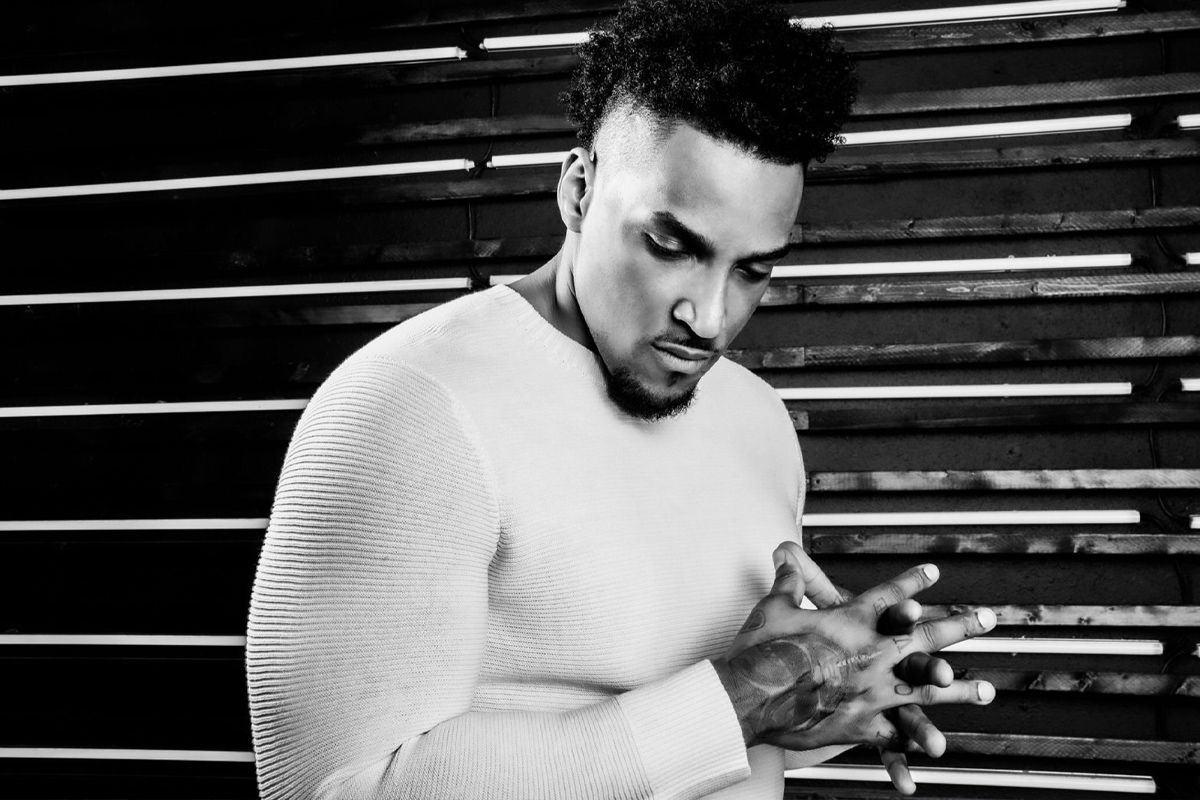 Black and white personal branding photography Joe Barksdale standing in front of wall with horizontal white light strips hands clasped