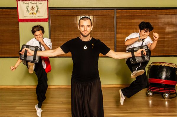 Branding Image Master Jason Campbell with two students kicking in mid air