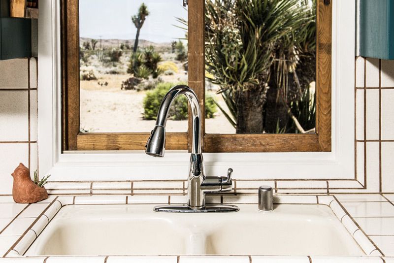 Place marketing image kitchen sink in front of window looking out to desert with cacti and Joshua Tree