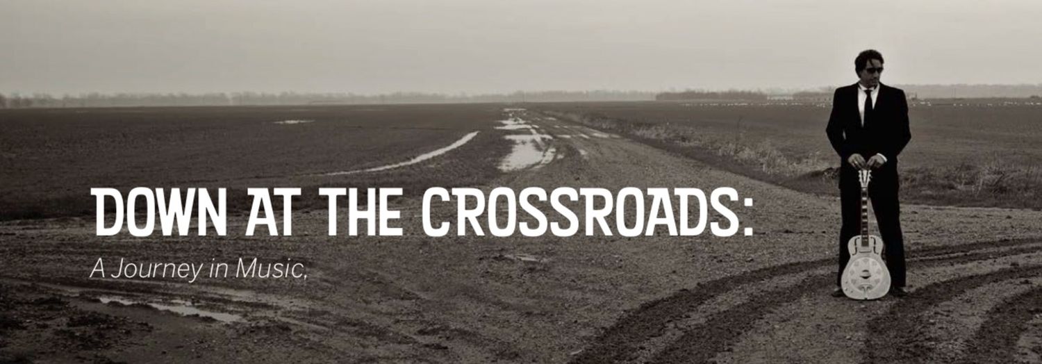 Promotional Image for Down At The Crossraods featuring Steve Azar standing wearing suit with hands resting on guitar standing upright
