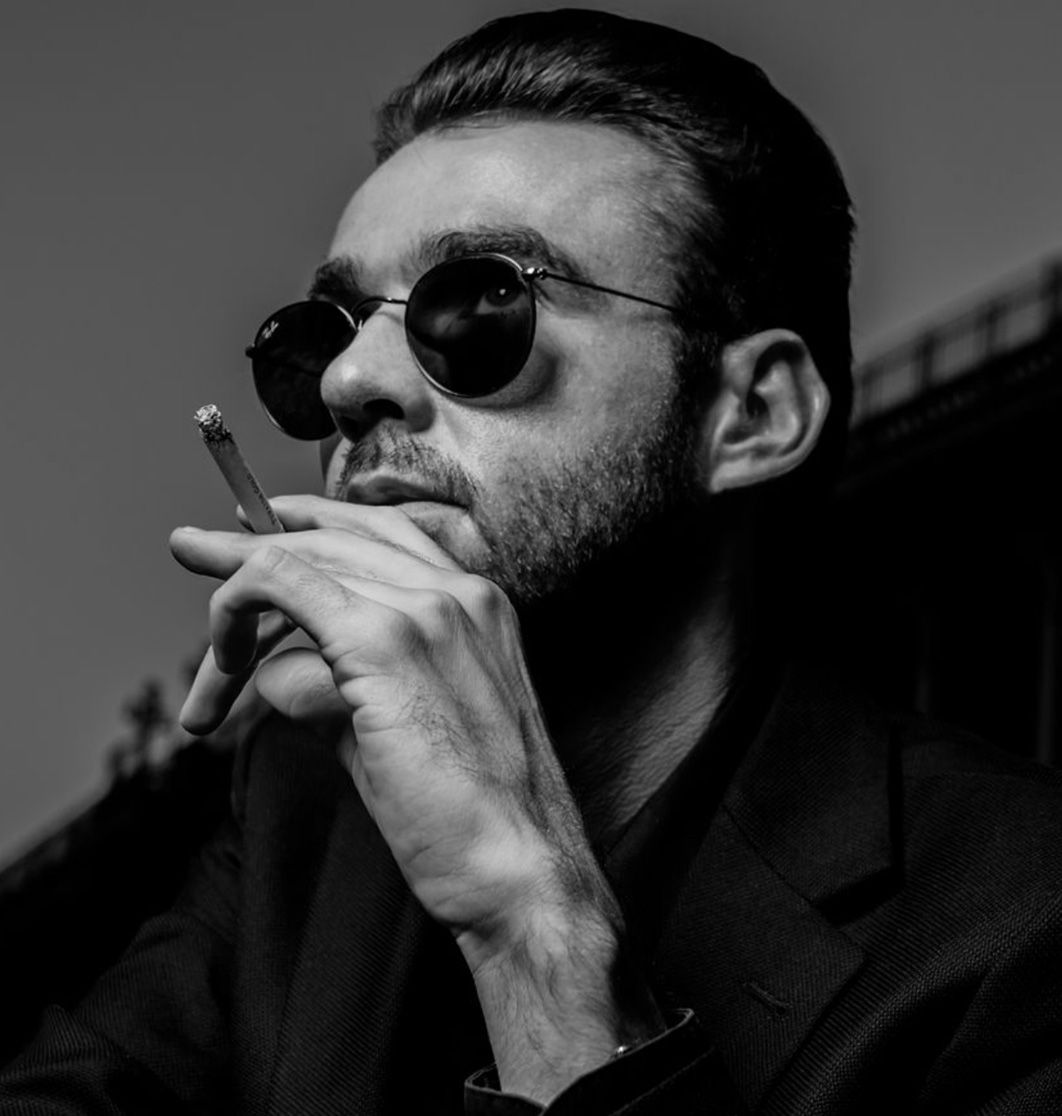 Black and white professional branding headshot author Chandler Morrison wearing sunglasses holding cigarette