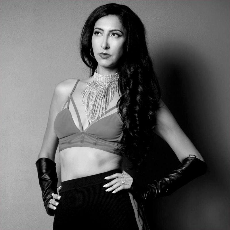 Black and white personal branding image Lana Zahia standing against gray backdrop hands on hips wearing bustier