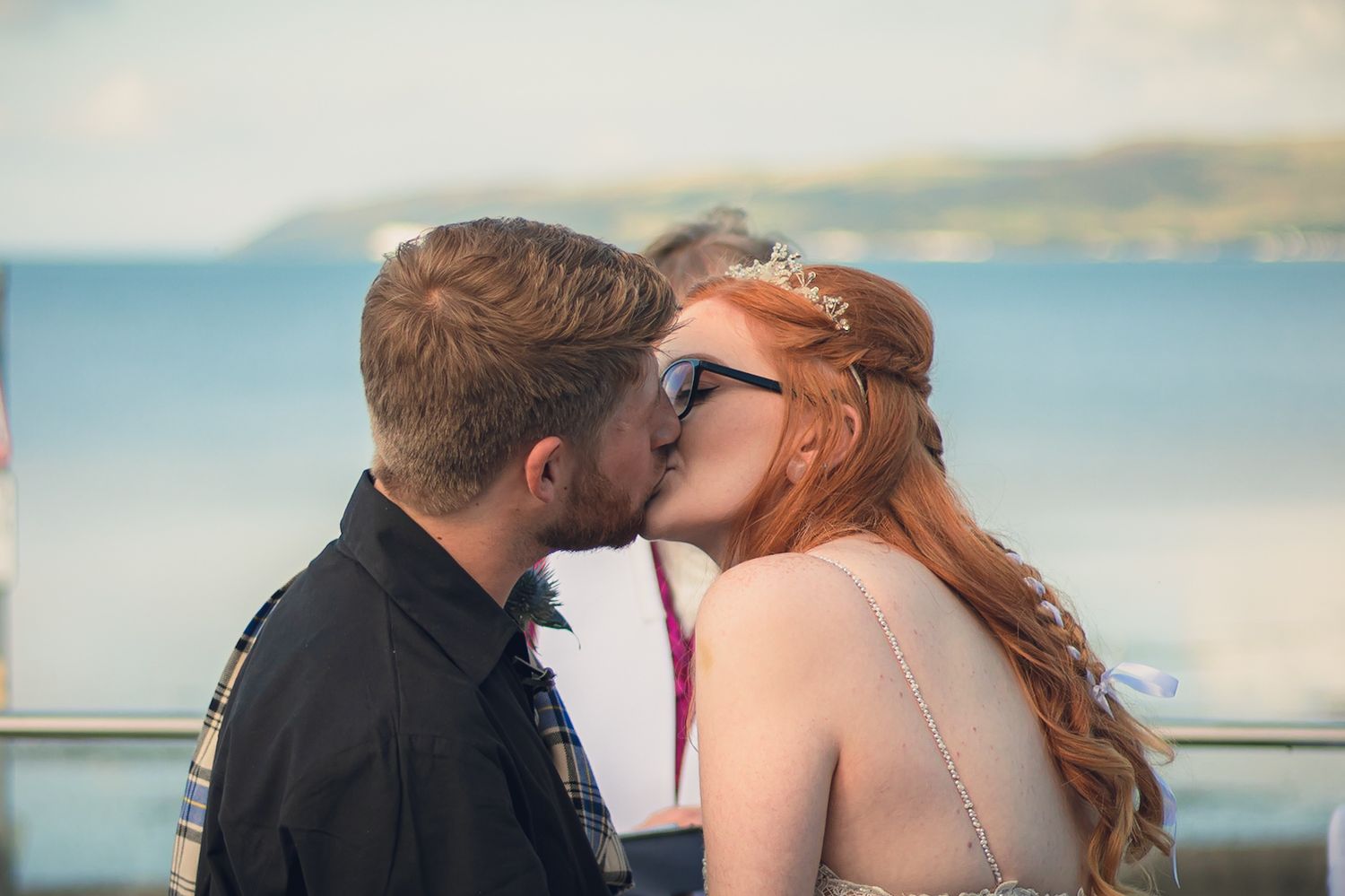 Bride and groom kissing with Loch Ryan, Dumfries and Galloway in the background