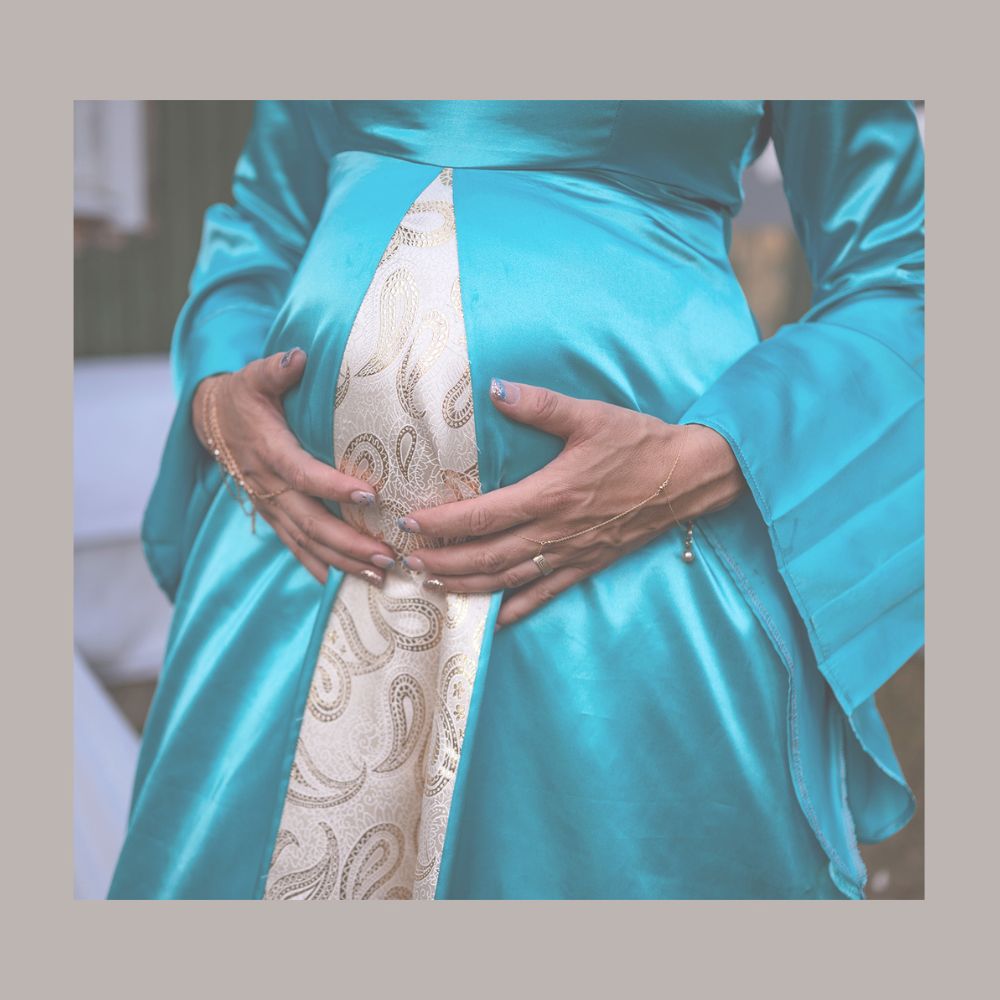 En blivande mamma håller sina händer på gravidmagen. Ett ögonblick att alltid minnas tillbaka till. Fotograferat utanför Lidköping.