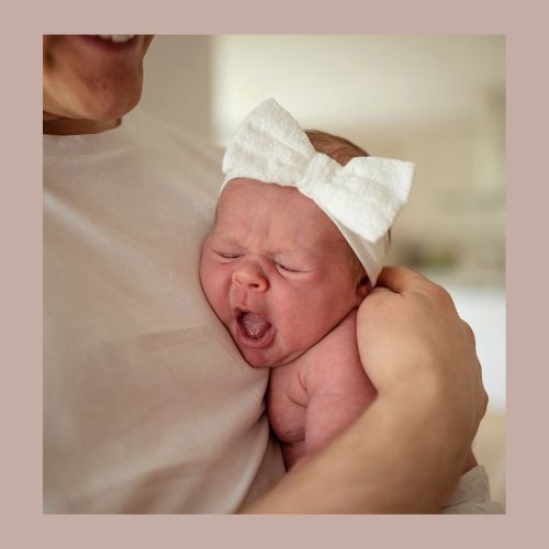 Trött liten tjej på nyföddfotografering. Gäspar i pappas famn. Fotograferat strax utanför Lidköping.