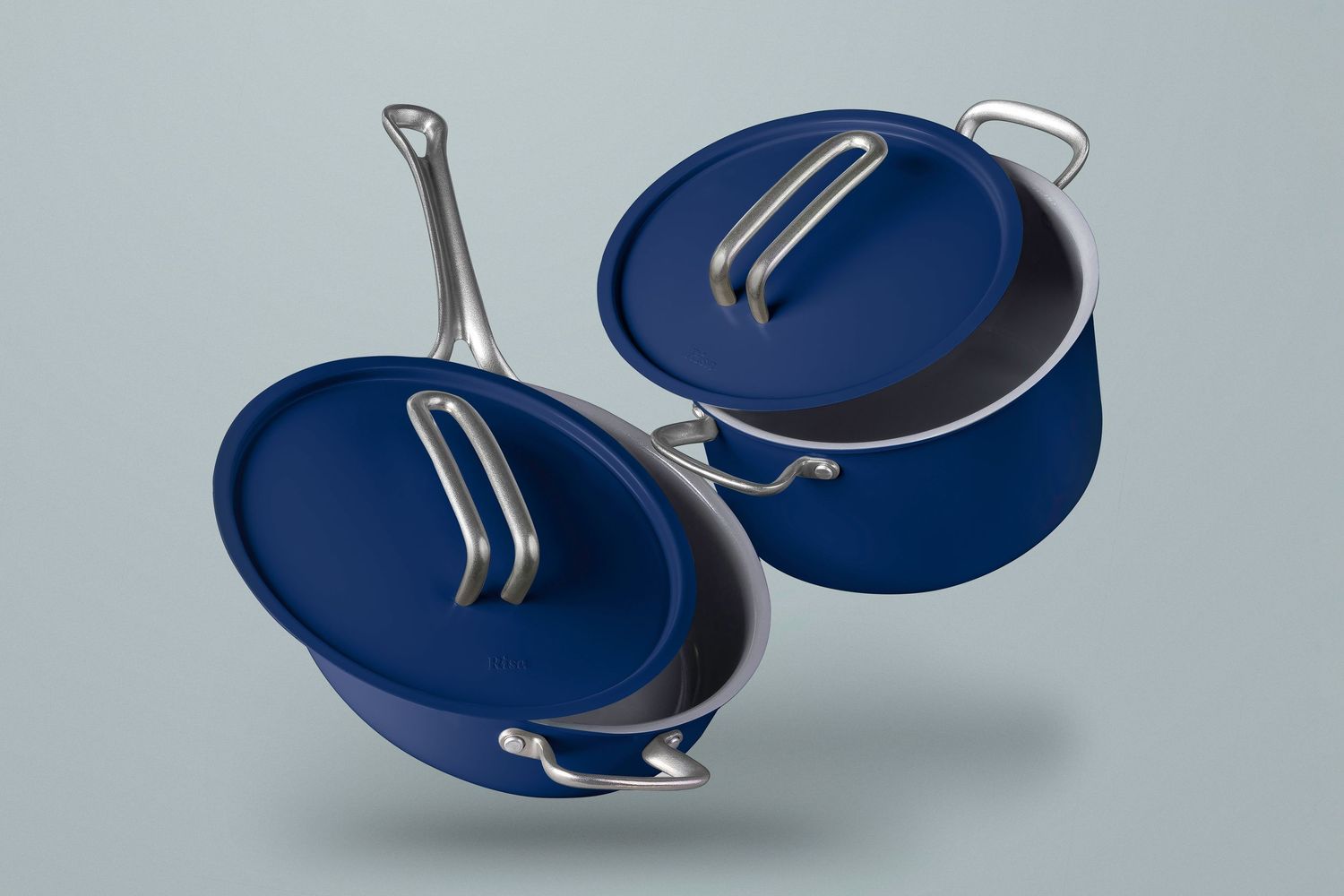 Two blue nonstick frying pans with stainless steel handles floating against a gray background.