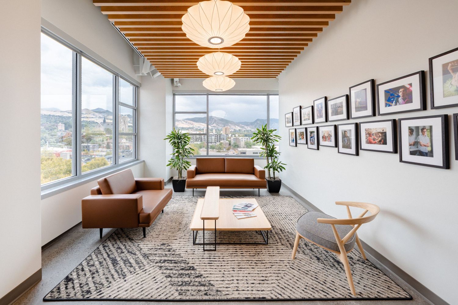 Modern office space with wood ceiling beams, pendant lights, and panoramic windows overlooking a cityscape.