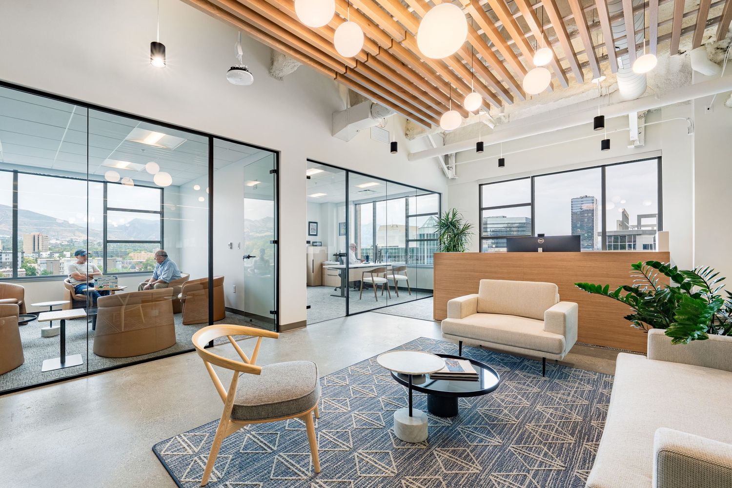 Modern office space with wood ceiling panels, glass walls, and contemporary furniture in an open floor plan layout.