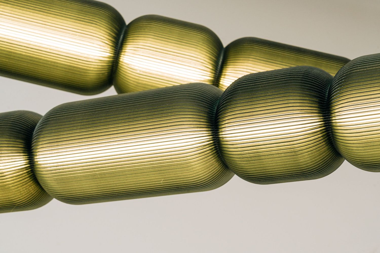 A series of metallic gold cylindrical shapes connected in a row create an abstract architectural design element.
