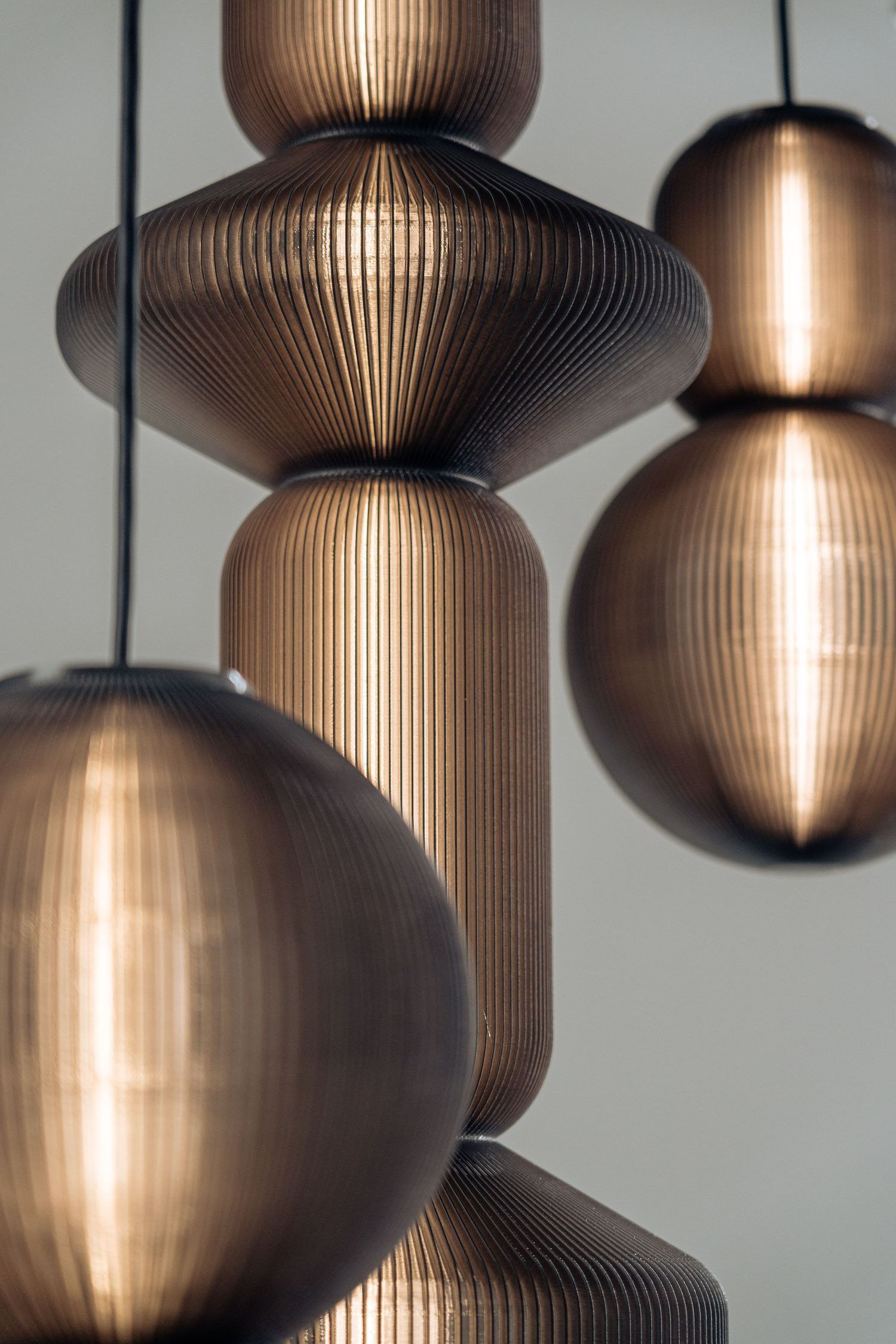 Modern pendant lights with ribbed bronze shades create dramatic shadows and warm ambient lighting in an interior space.