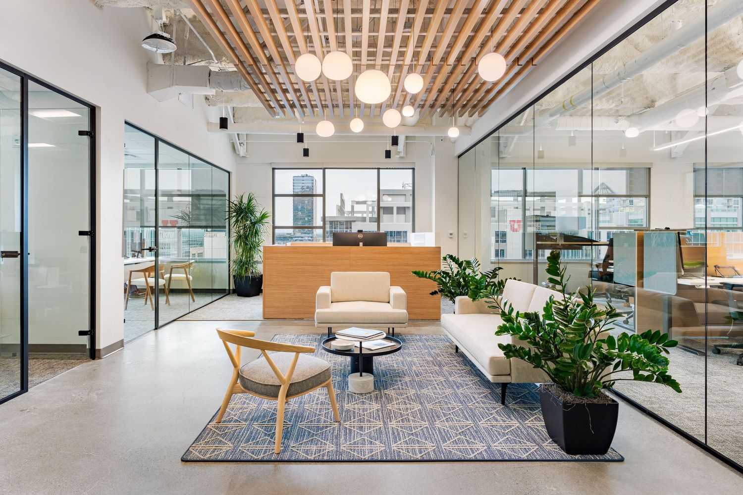 Modern office interior with wood slat ceiling, glass walls, and contemporary furniture in an open workspace design.
