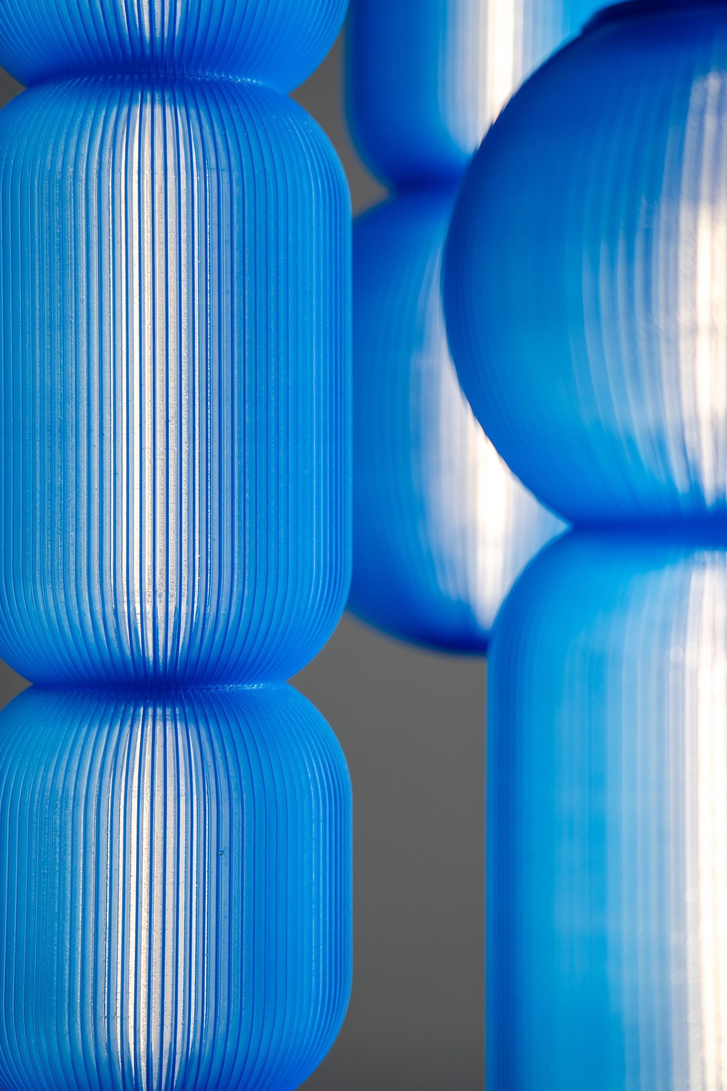 Close-up view of bright blue cylindrical paper lanterns with ribbed texture creating an abstract pattern.