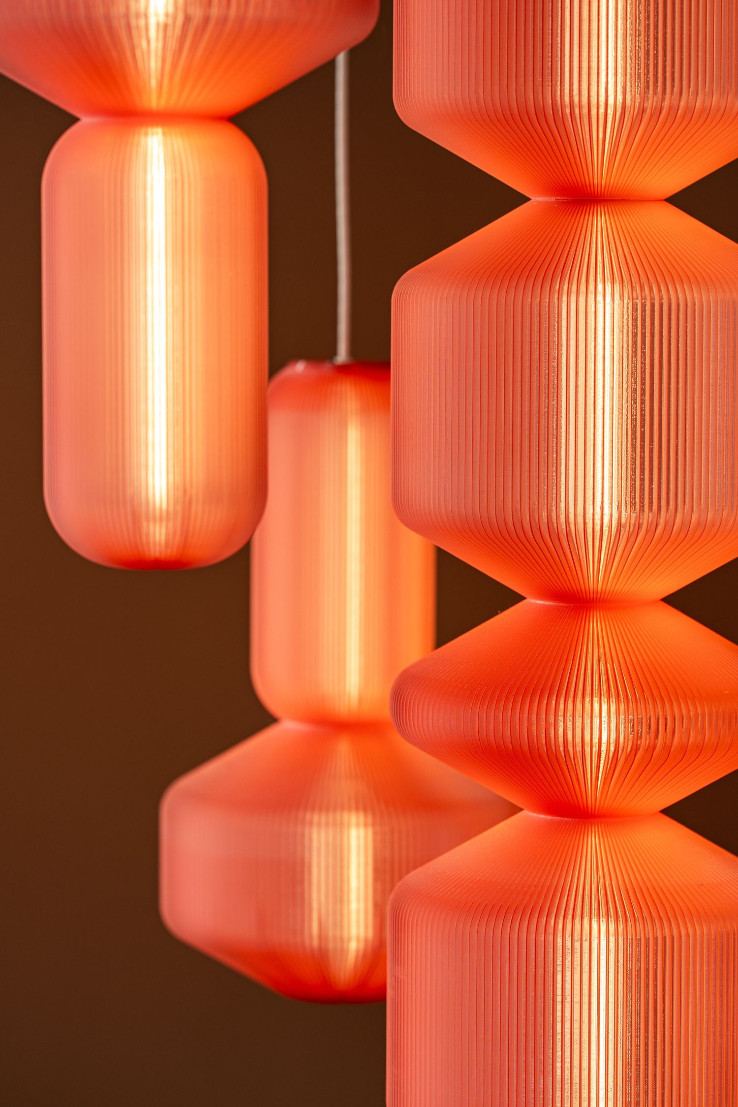 A series of glowing red paper lanterns with ribbed textures hanging in a row against a dark background.