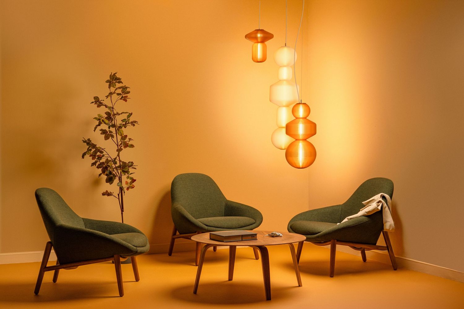Mid-century modern lounge chairs arranged with pendant lighting creating a warm, retro atmosphere against orange carpet.