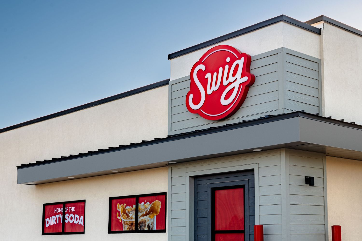 A Swirl frozen yogurt shop exterior with red signage and gray siding against a blue sky.