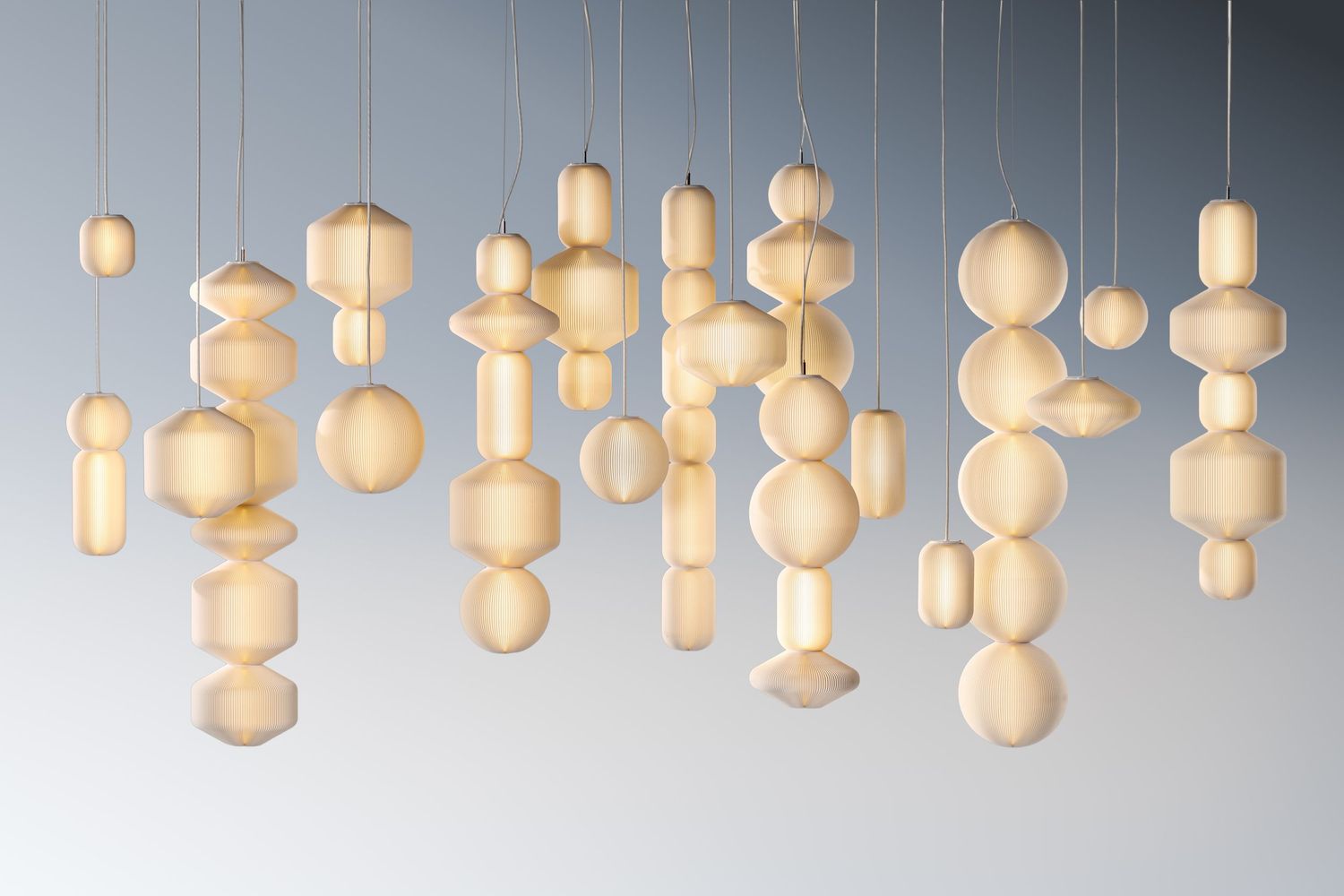 Modern white glass pendant lights arranged in a row create an elegant illuminated display against a gray background.