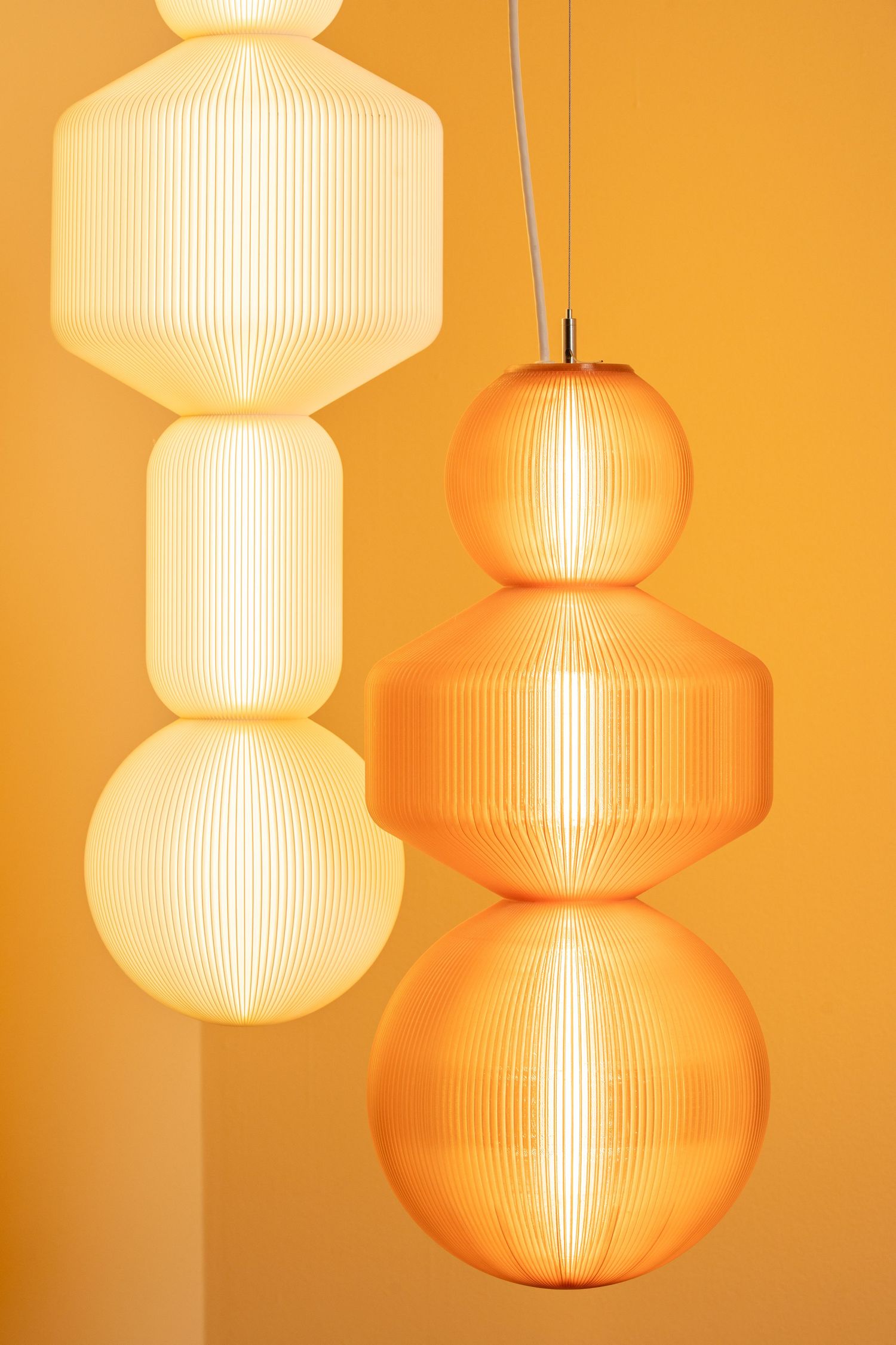 Modern pendant lamps with ribbed glass shades cast a warm orange glow against a peach-colored wall.