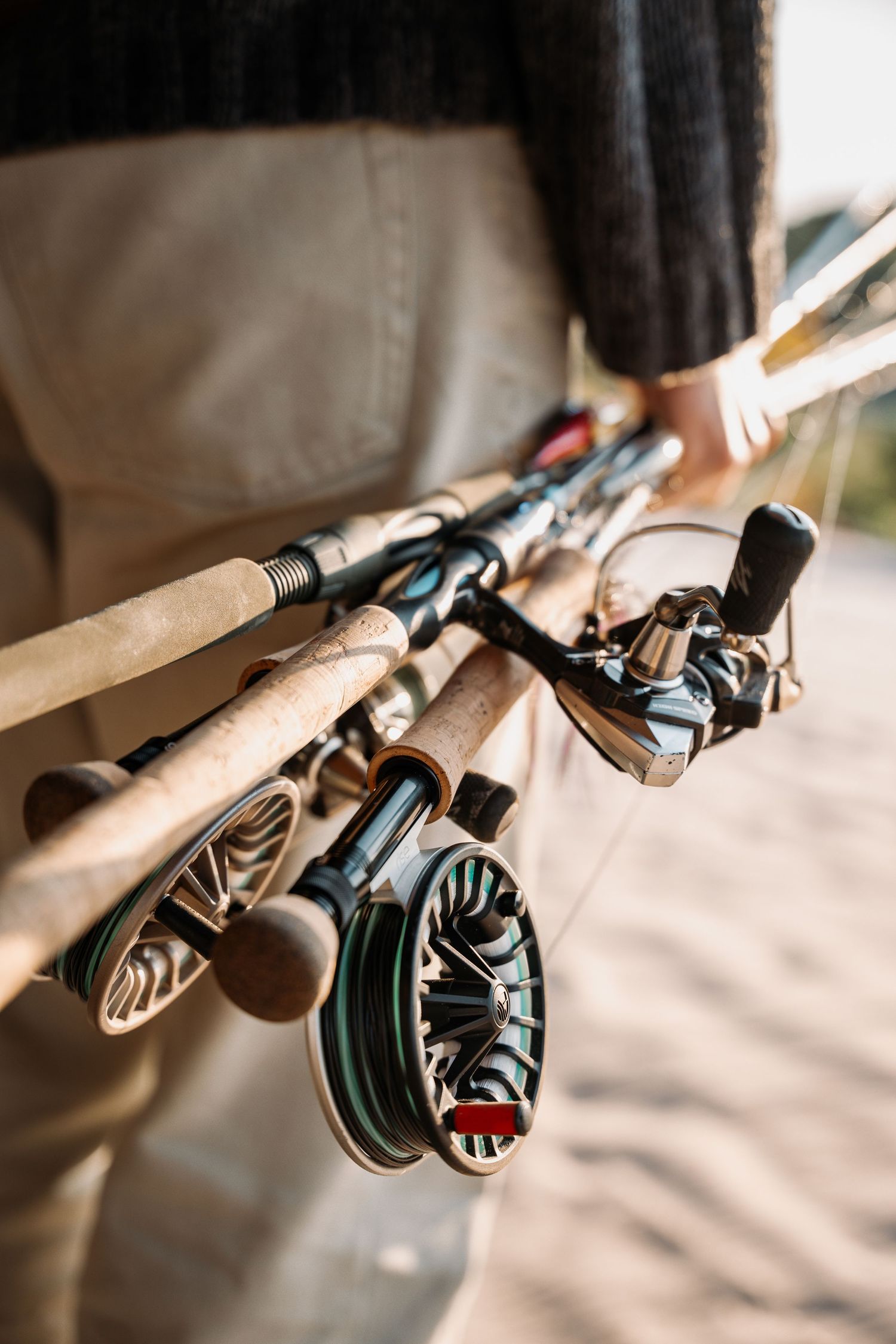 Close-up view of fishing reels and rods stacked together with detail of spinning reel mechanism.