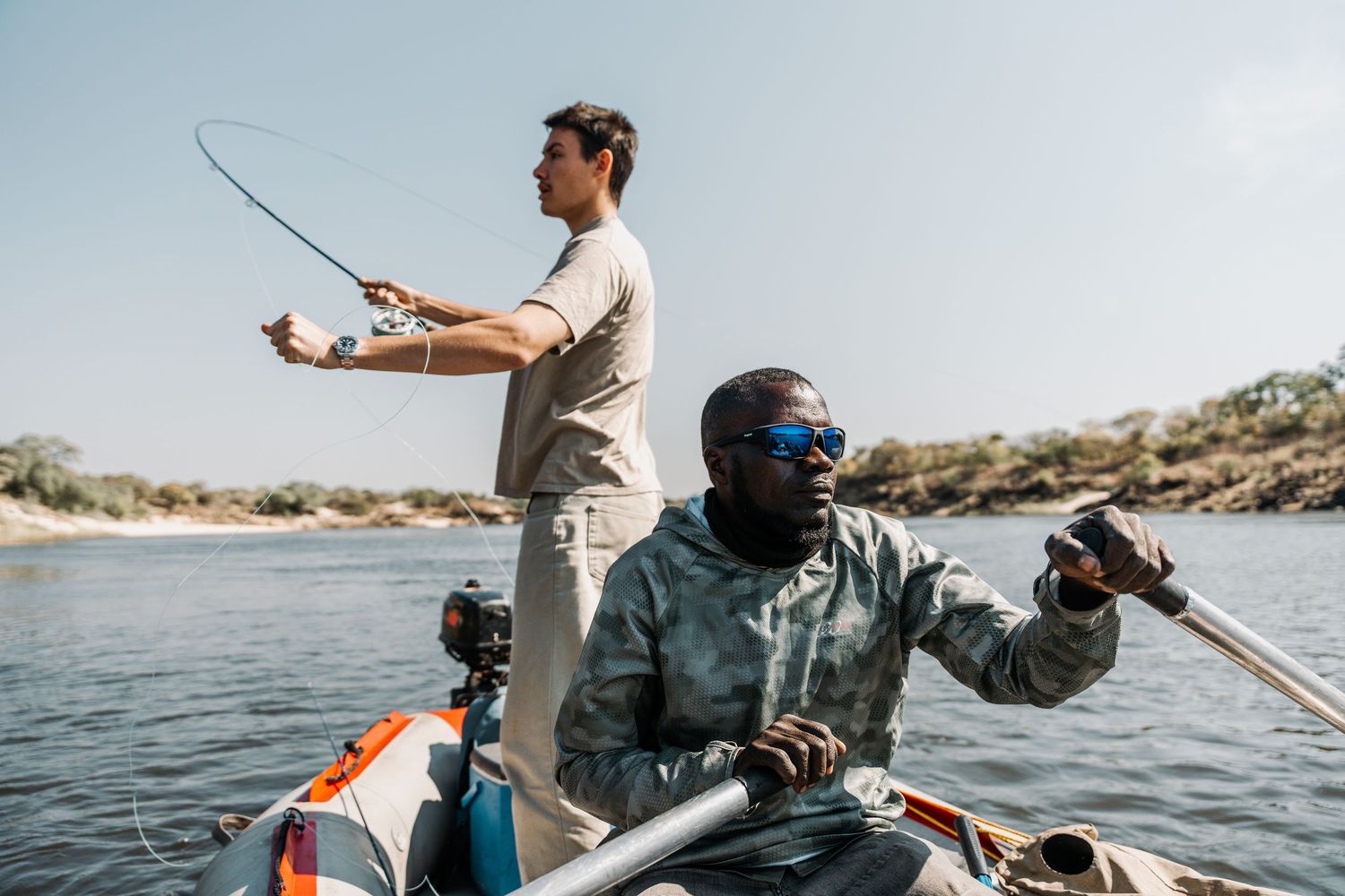 A group of anglers cast fishing lines from a boat while enjoying a sunny day on the water.