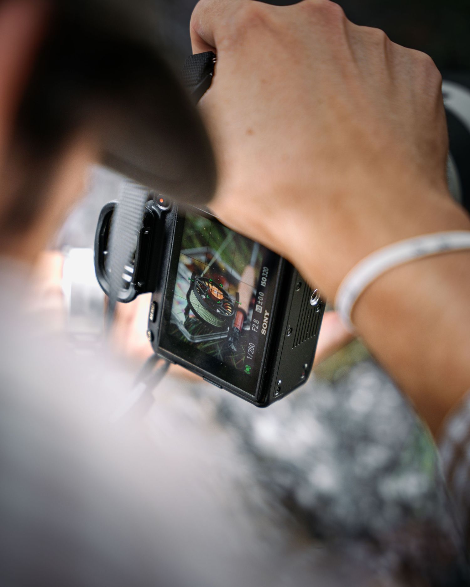 Blurred closeup view shows someone holding a digital camera focused on its LCD display screen.