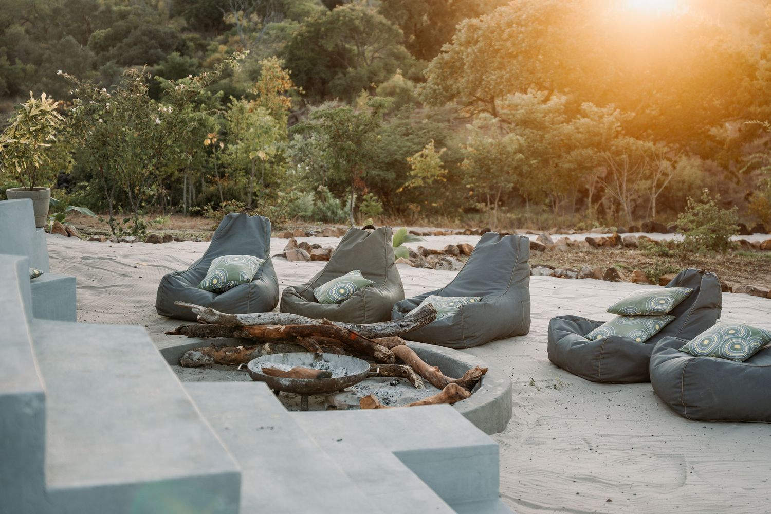 Bean bag chairs arranged outdoors on a stone patio with sunlight filtering through trees.