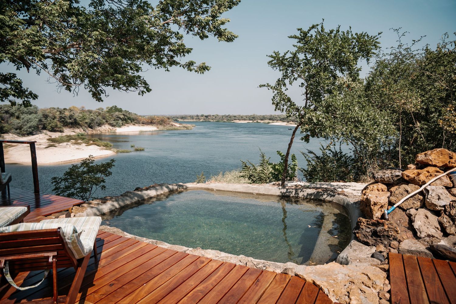 Wooden deck overlooking a scenic coastal bay with turquoise waters and rocky shoreline.