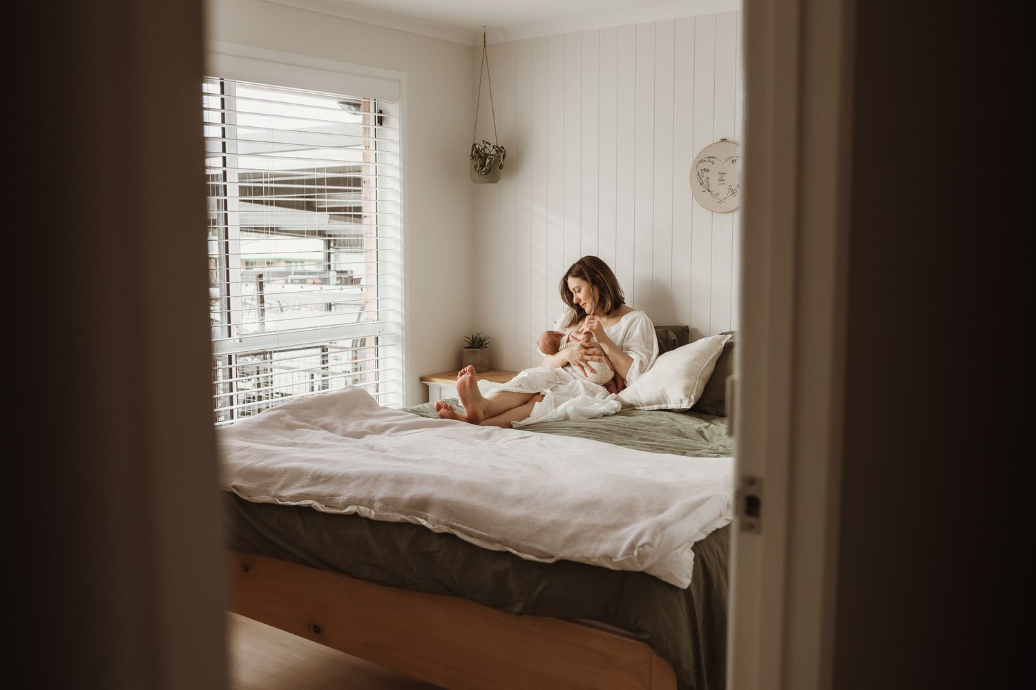 A cozy morning scene in a sunlit bedroom with white bedding and natural light streaming through the window.