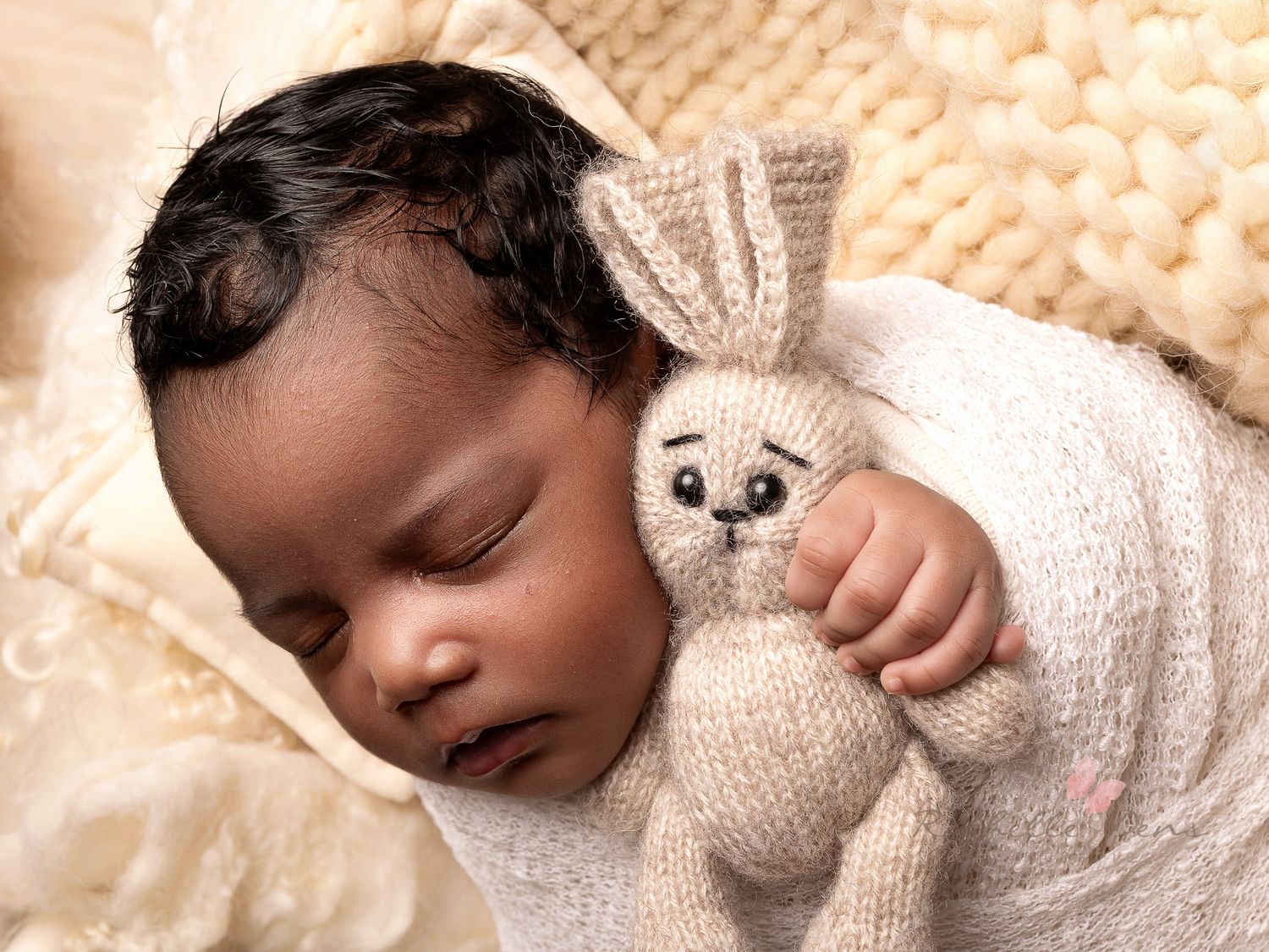 Sleeping baby in white knit sweater lying on soft beige blanket.
