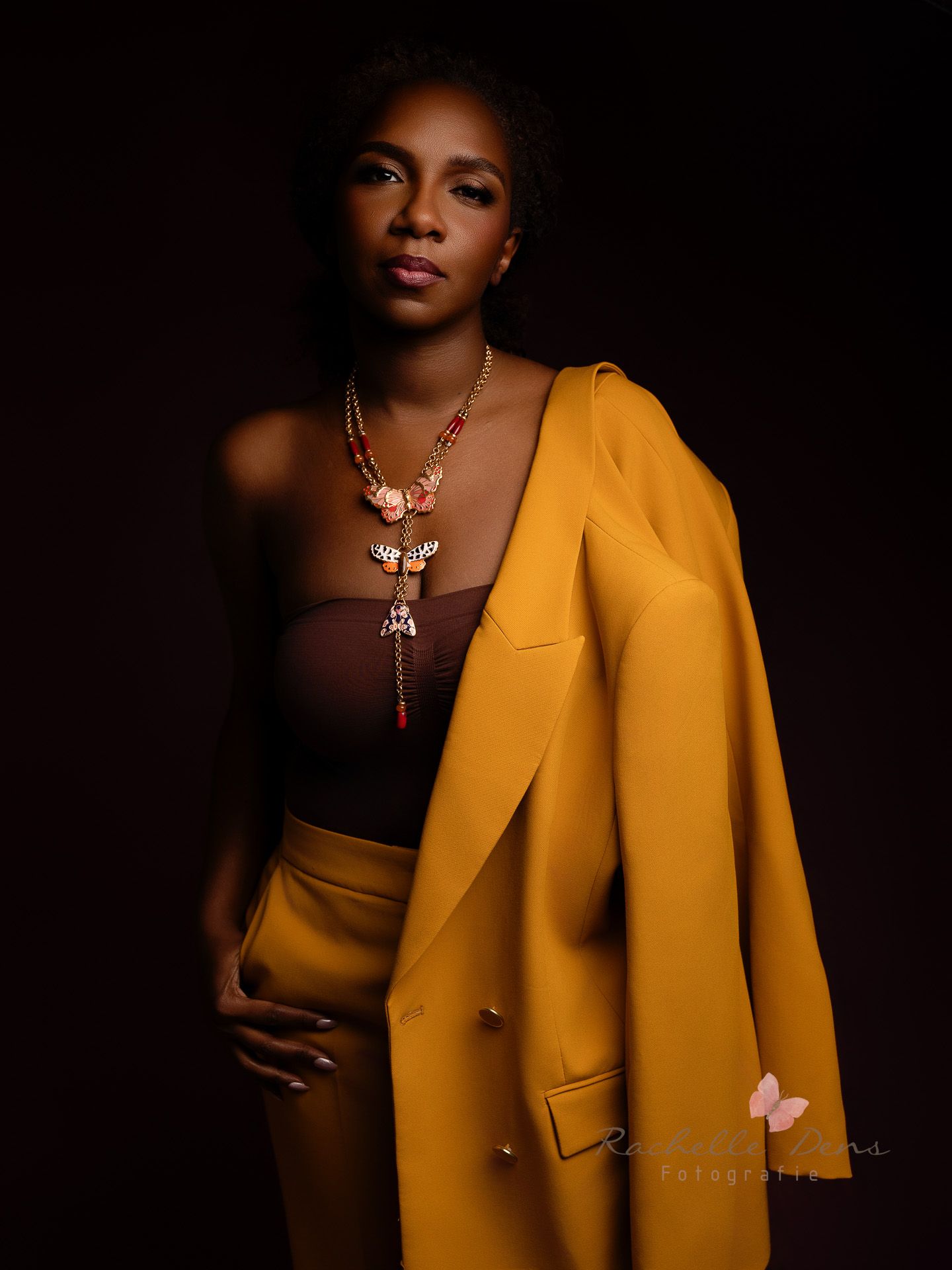 A portrait series showing a person in a mustard yellow blazer against a dark background with elegant jewelry.
