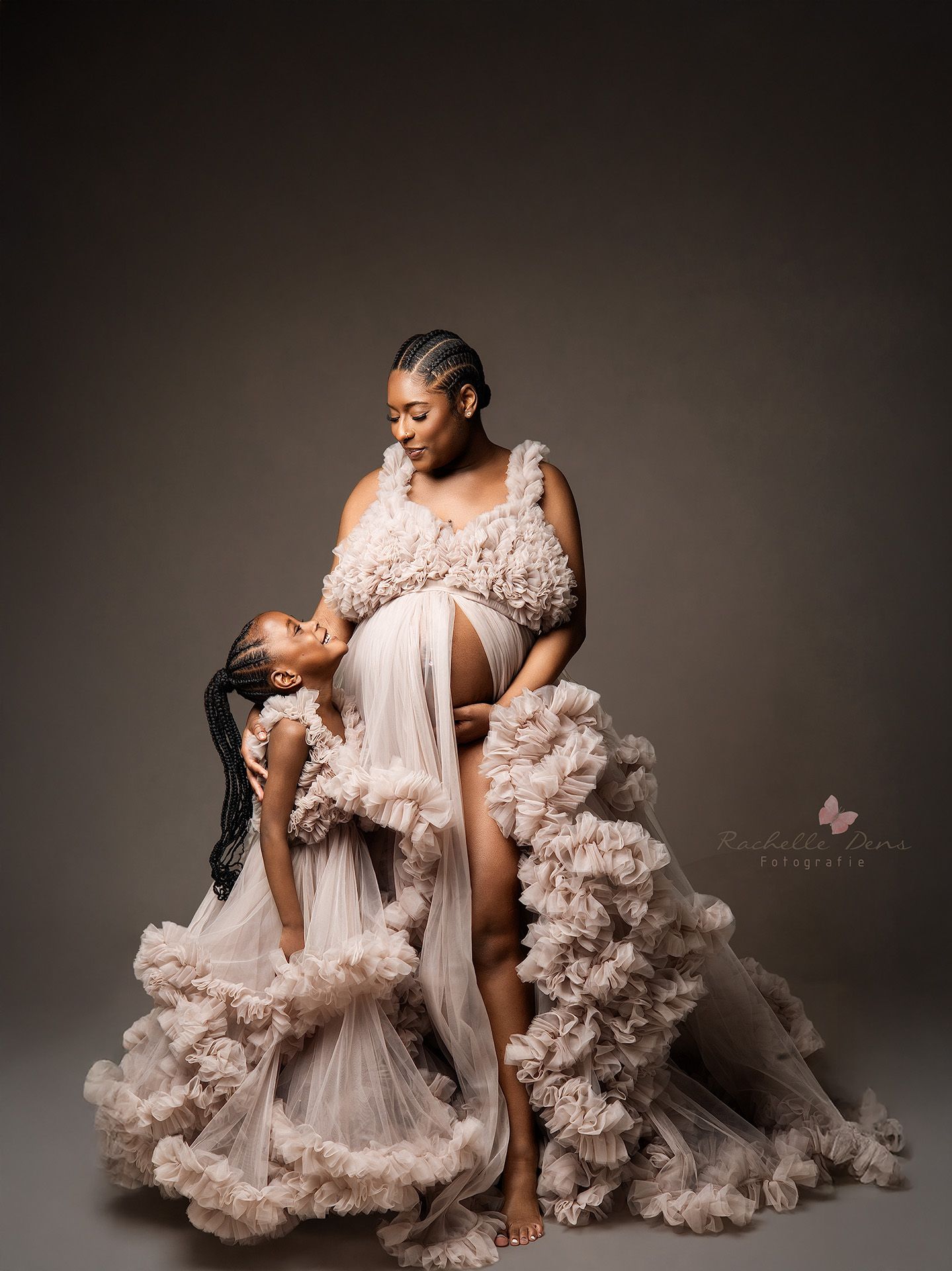 A mother and daughter share a tender moment in matching ethereal ruffle gowns during an elegant studio portrait session.