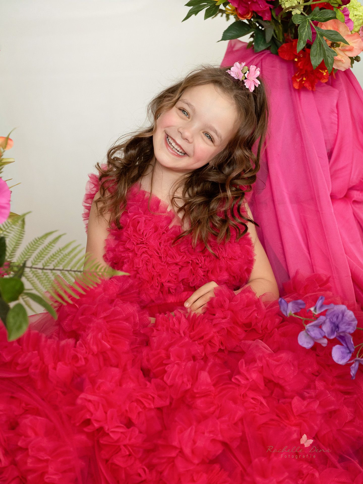 A collage of four photos showing a child in a vibrant red ruffled dress posing with floral decorations and pink accents.
