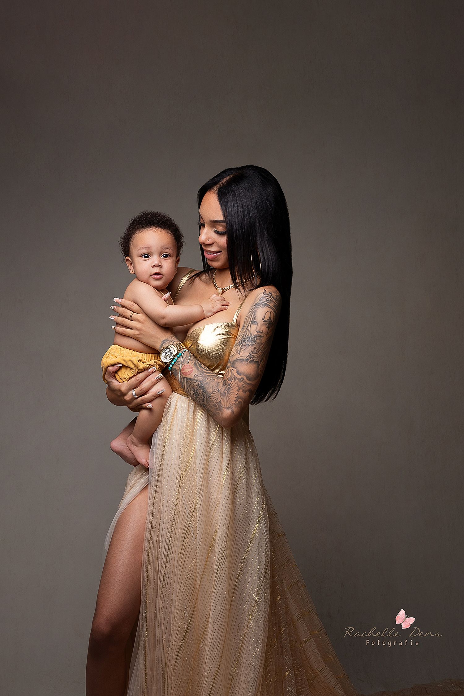 A tender moment captured between parent and child in a glamorous gold dress during studio session.