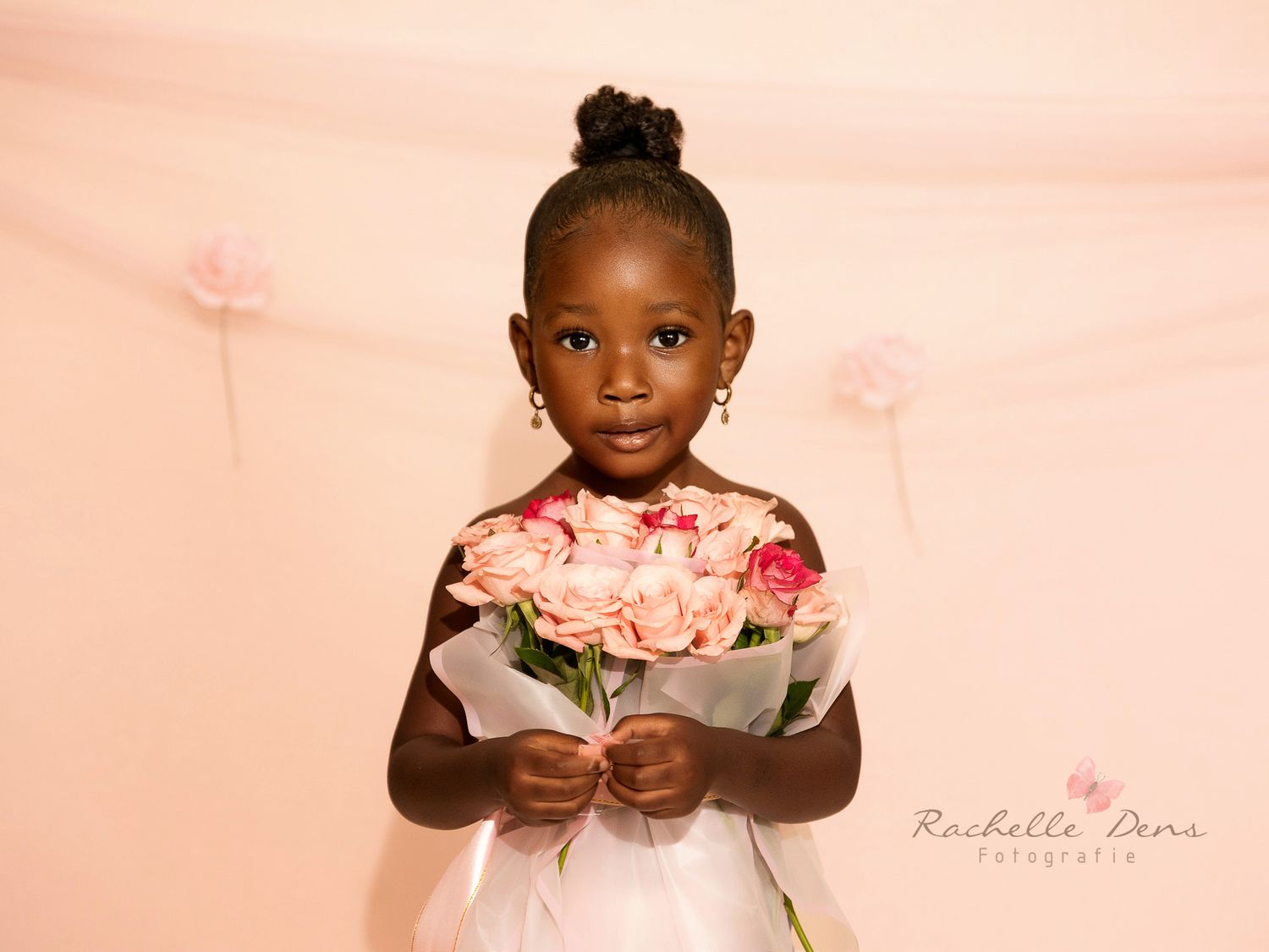 A child in a white dress poses with pink roses in a delicate and artistic photo series.