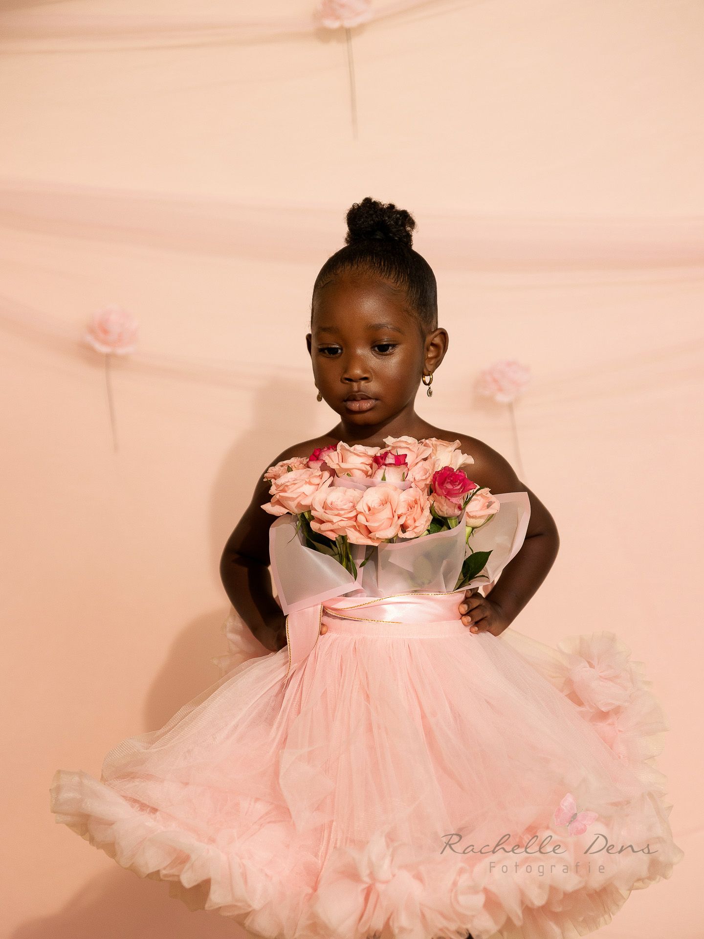 A child wearing a pink tulle dress with floral details poses in multiple shots against a soft pink background.