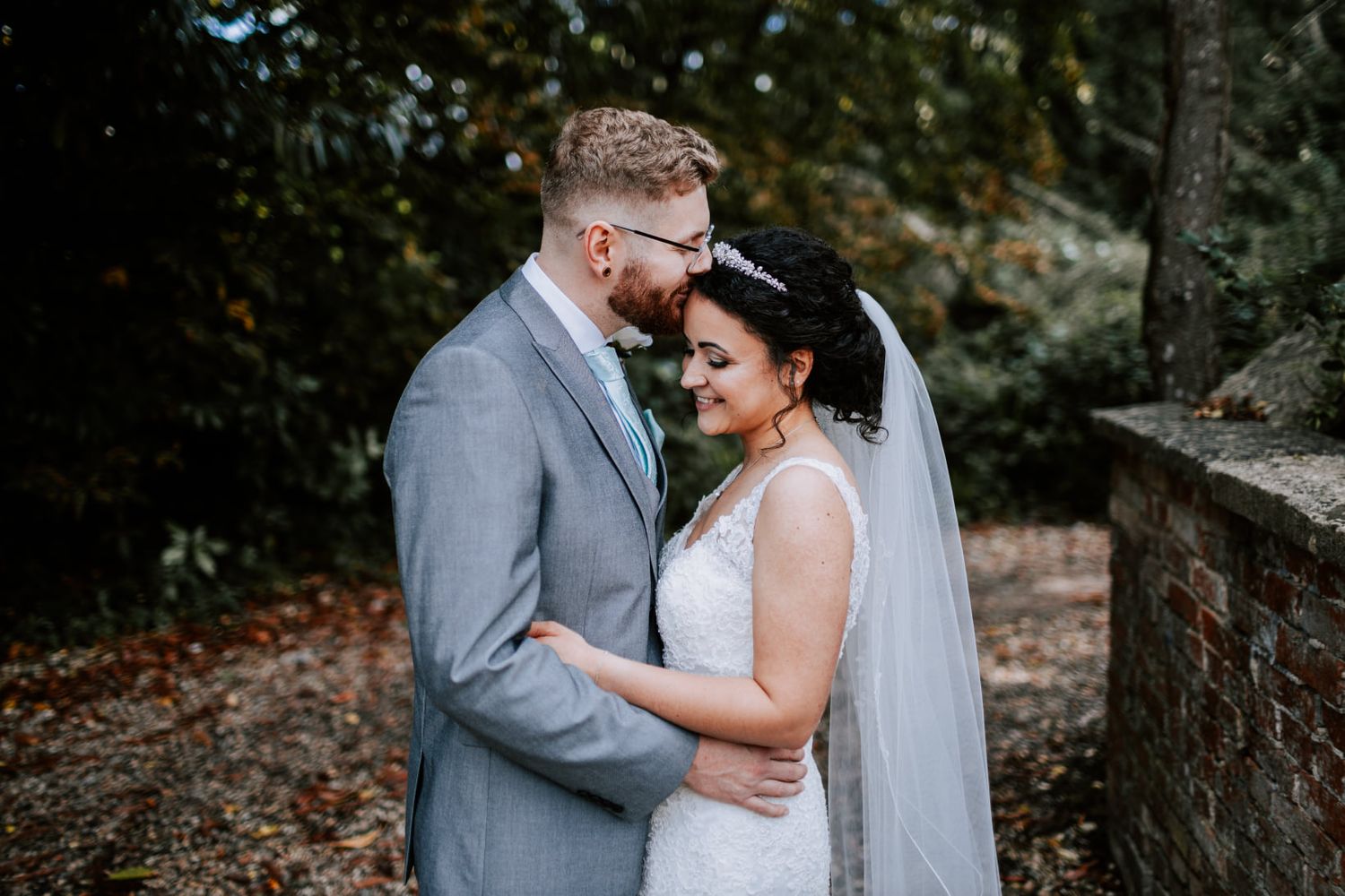 Romantic wedding couple embraces in a forest setting.