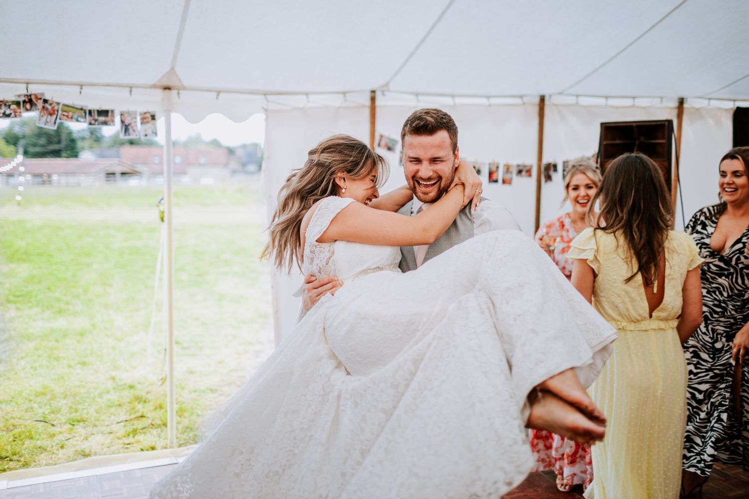 Joyful first dance moment under white tent at outdoor wedding reception.