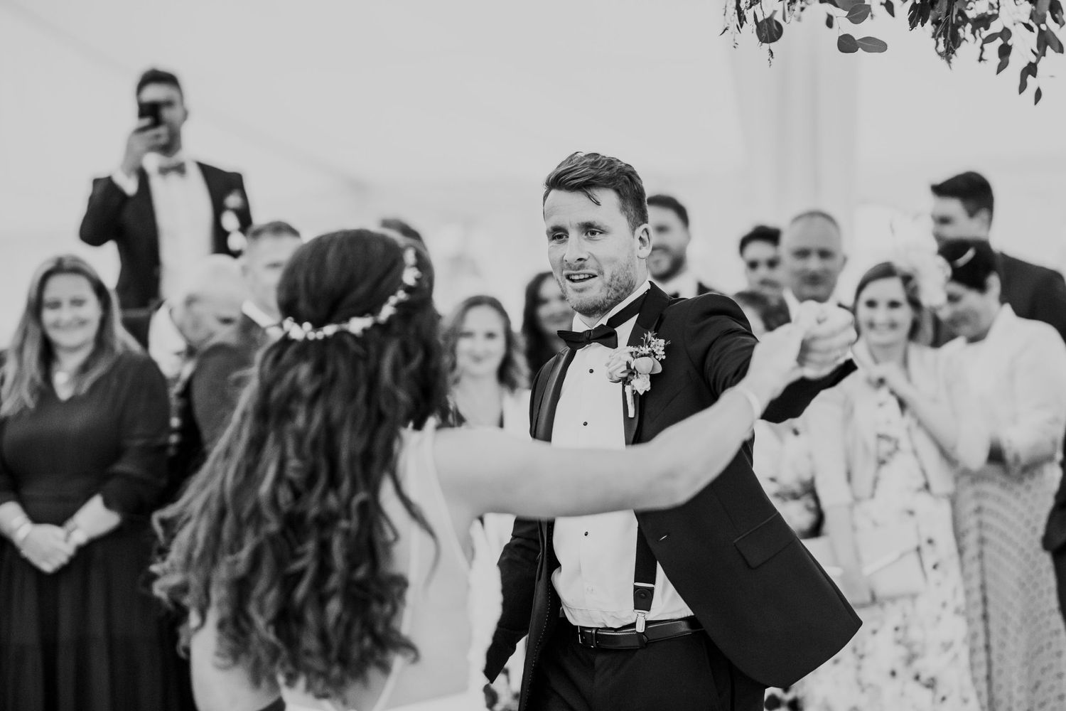 Wedding guests watch a celebratory first dance at an outdoor reception.