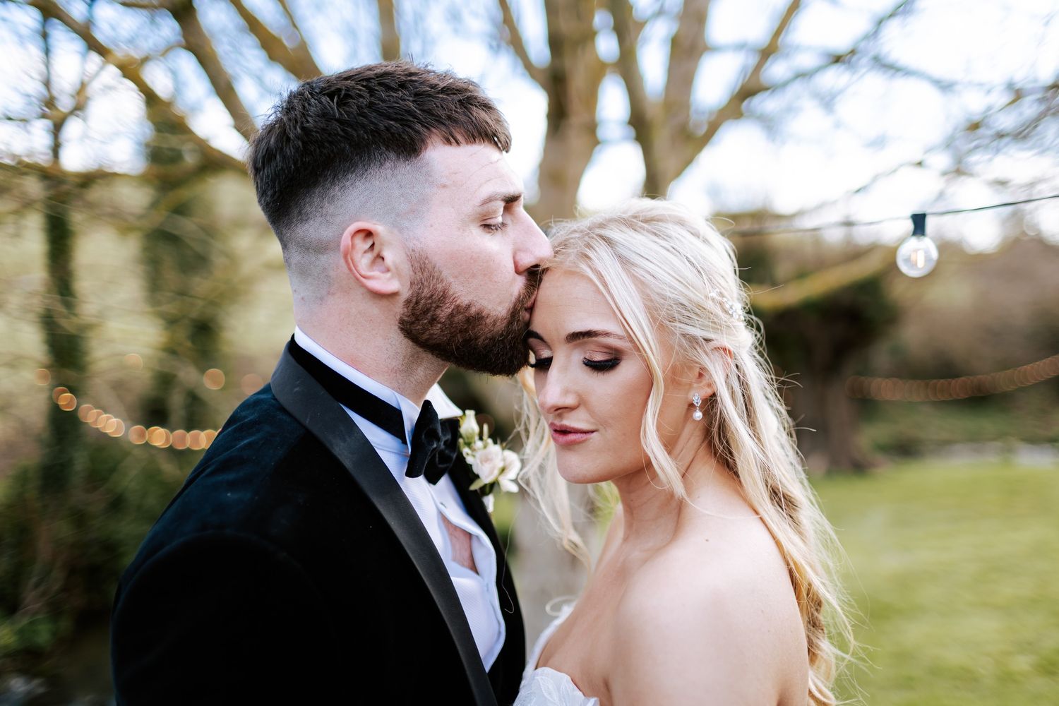 Intimate black and white portrait of couple against natural outdoor backdrop.