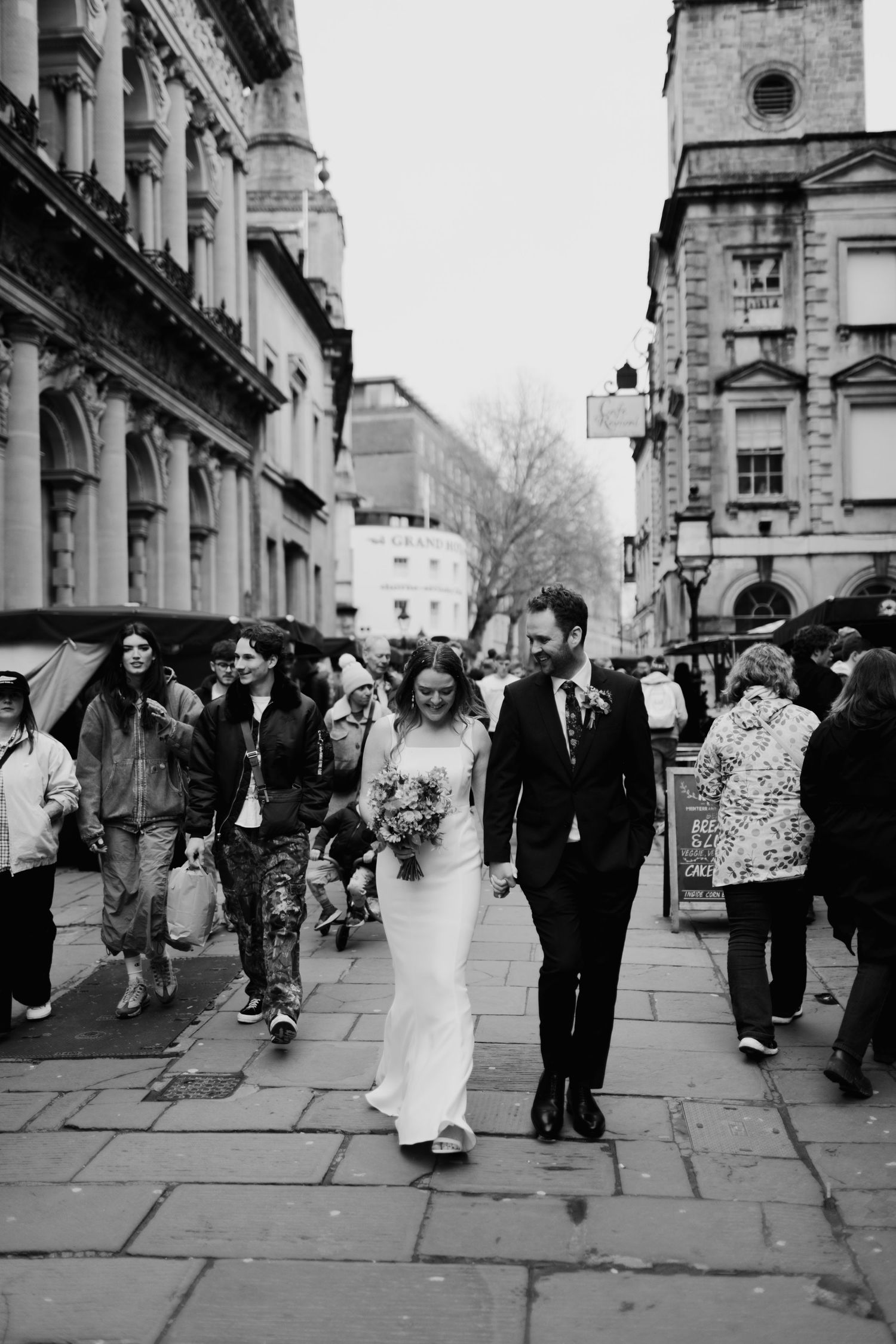 Wedding party walking through historic city streets with classic architecture in black and white.