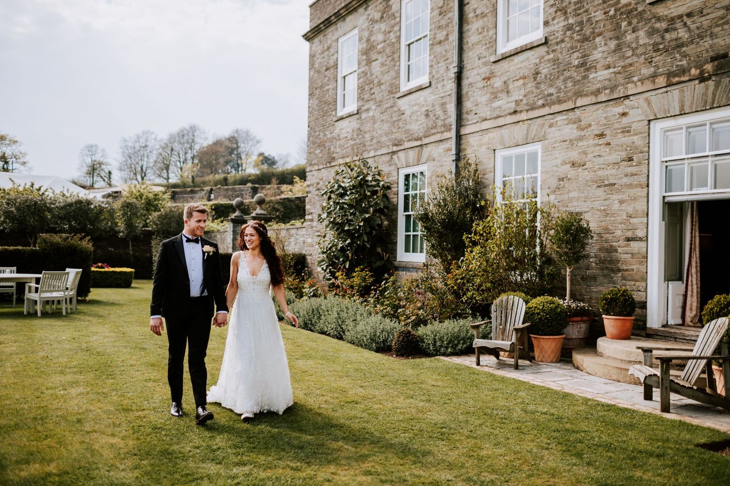 Wedding couple walking through the grounds of a rustic stone country estate.