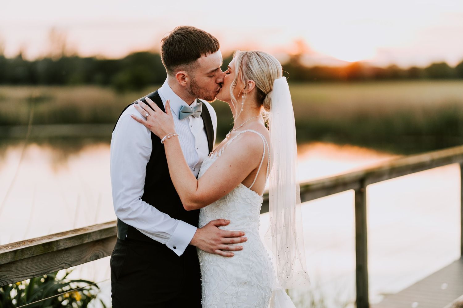 Couple shares an intimate sunset moment on a dock by the water.