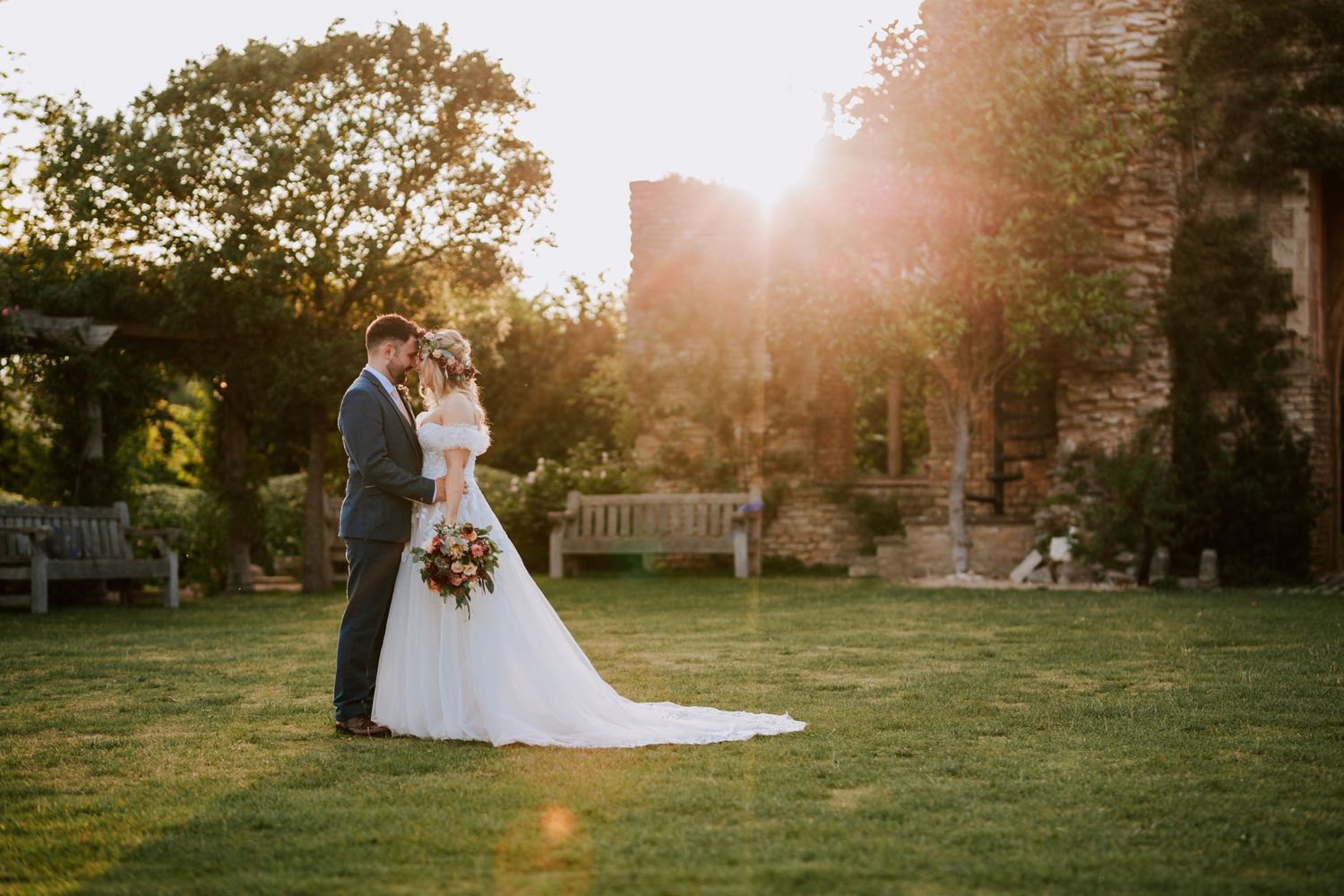 Golden hour wedding portraits in a lush garden setting with dramatic sunlight.