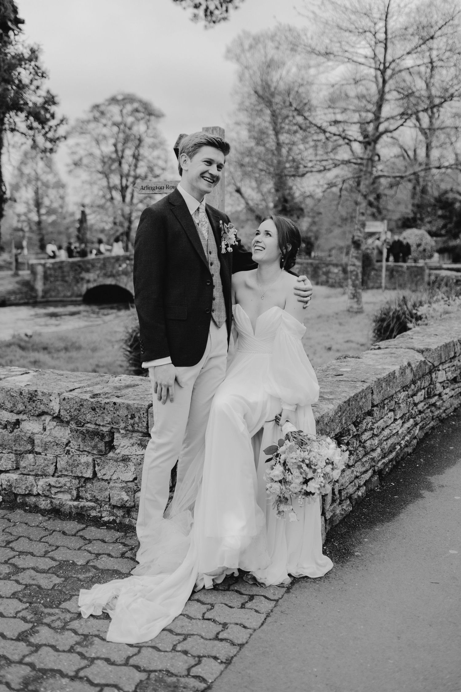 Romantic wedding portraits captured against rustic stone wall and natural garden backdrop.