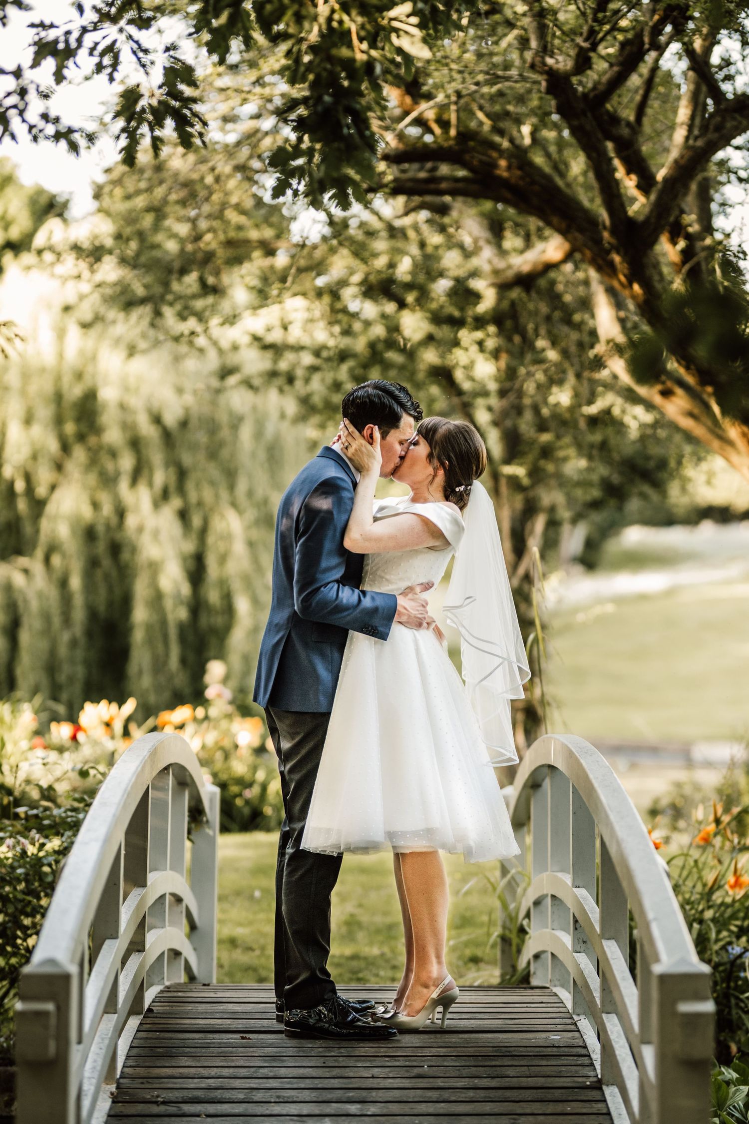 Intimate wedding photos of couple sharing kisses on rustic white bridge.