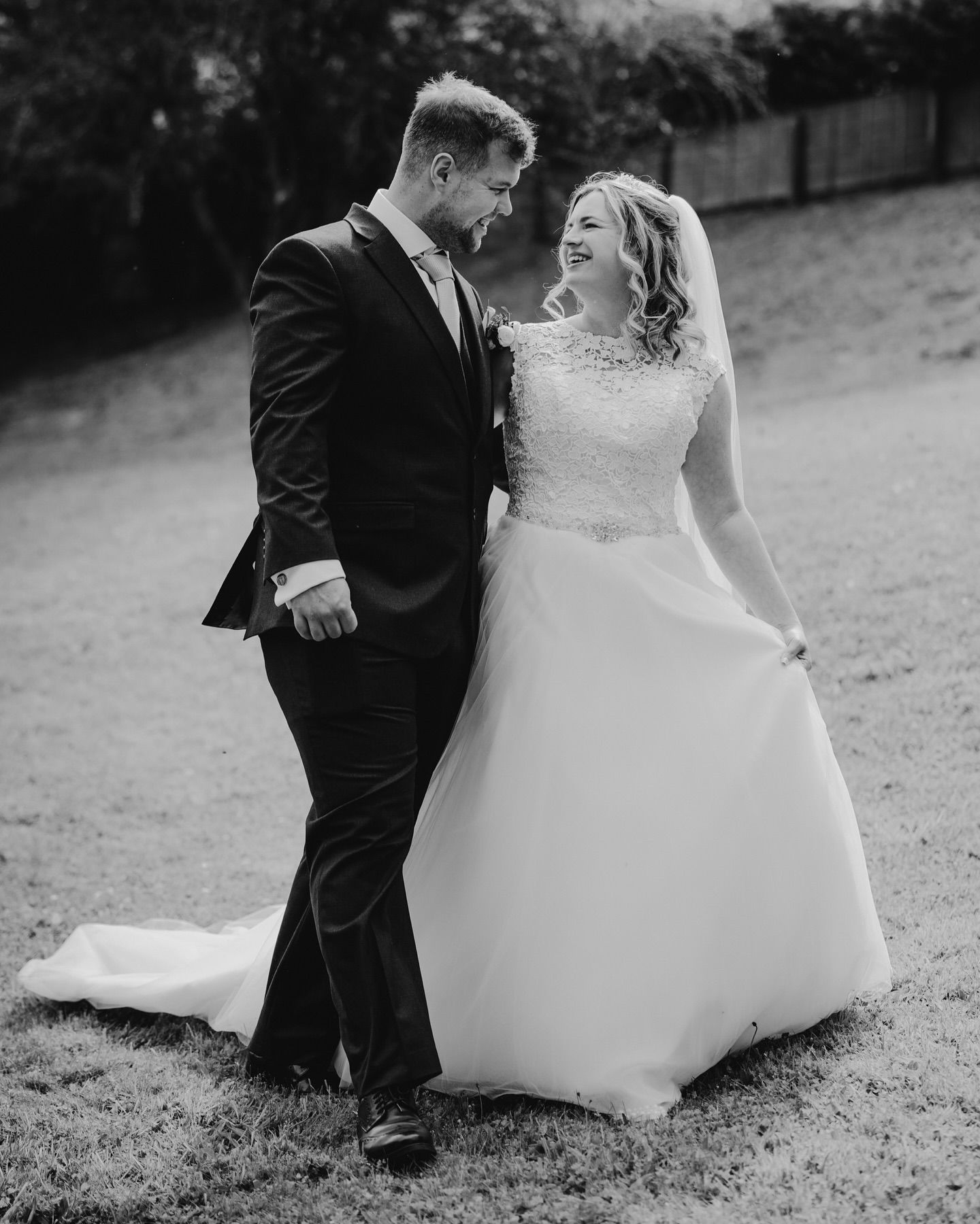 A black and white portrait capturing a joyful moment between a couple on their wedding day.