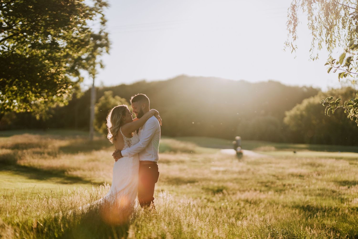 Romantic sunset wedding photo in a golden meadow with glowing backlight.